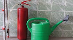 &ldquo;Watering can and fire extinguisher stand in front of wall&rdquo;