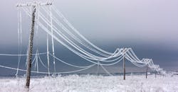 Broken phase electrical power lines with hoarfrost on the wooden electric poles on countryside in the winter after storm.