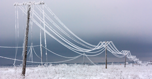 Broken phase electrical power lines with hoarfrost on the wooden electric poles on countryside in the winter after storm.