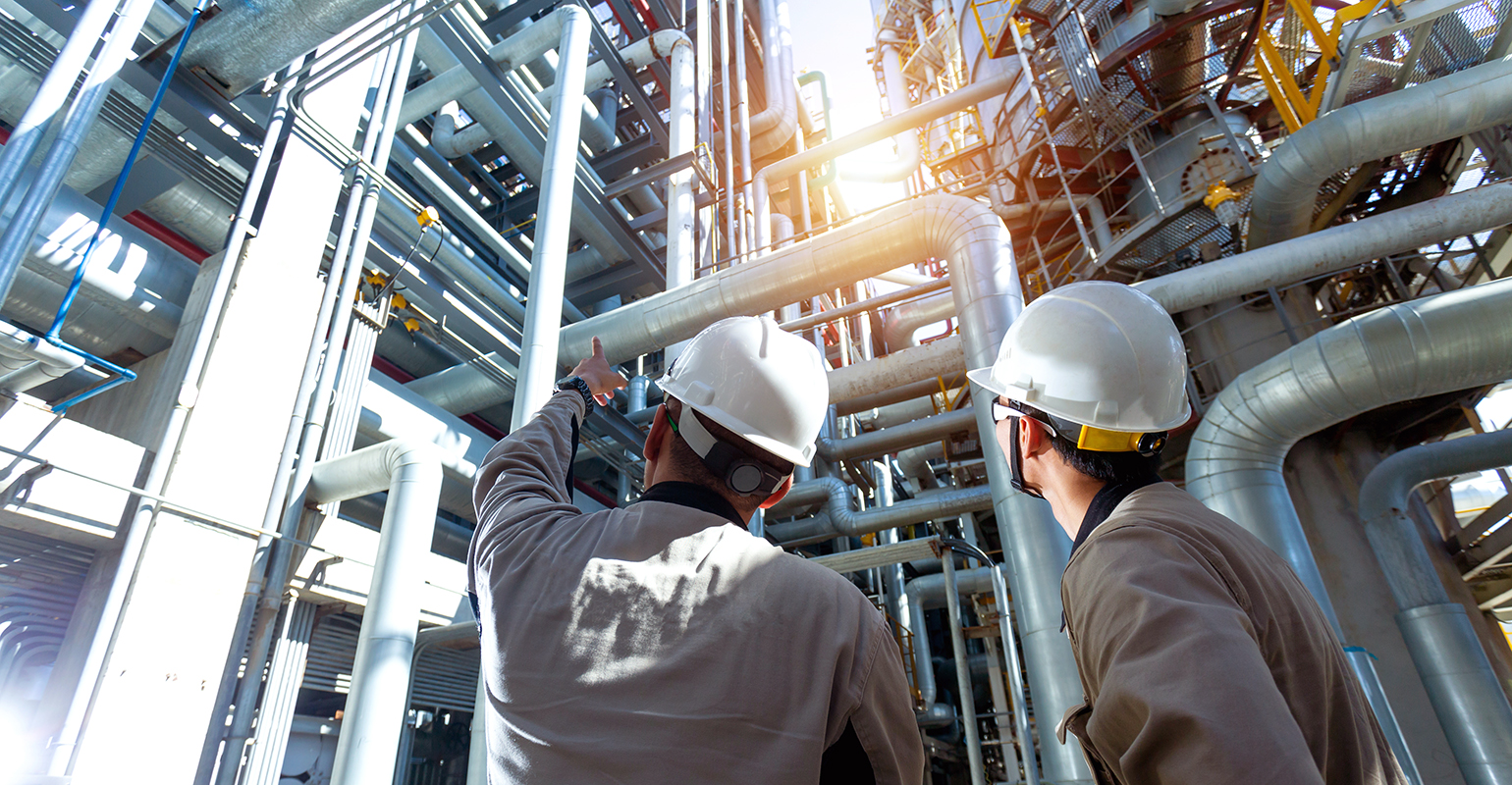 Industrial engineer or worker checking pipeline at oil-and-gas refinery plant.