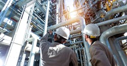 Industrial engineer or worker checking pipeline at oil-and-gas refinery plant.