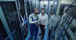 Two techs study Big Data servers. Two techs study Big Data servers.