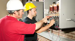 Engineer training apprentices on CNC machine.