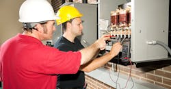 Engineer training apprentices on CNC machine. Engineer training apprentices on CNC machine.