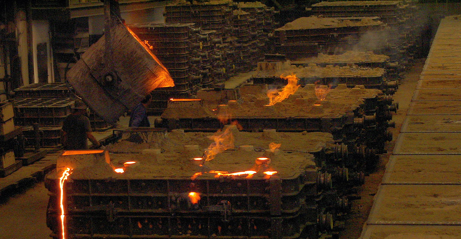 Pouring hot metal into sand molds.