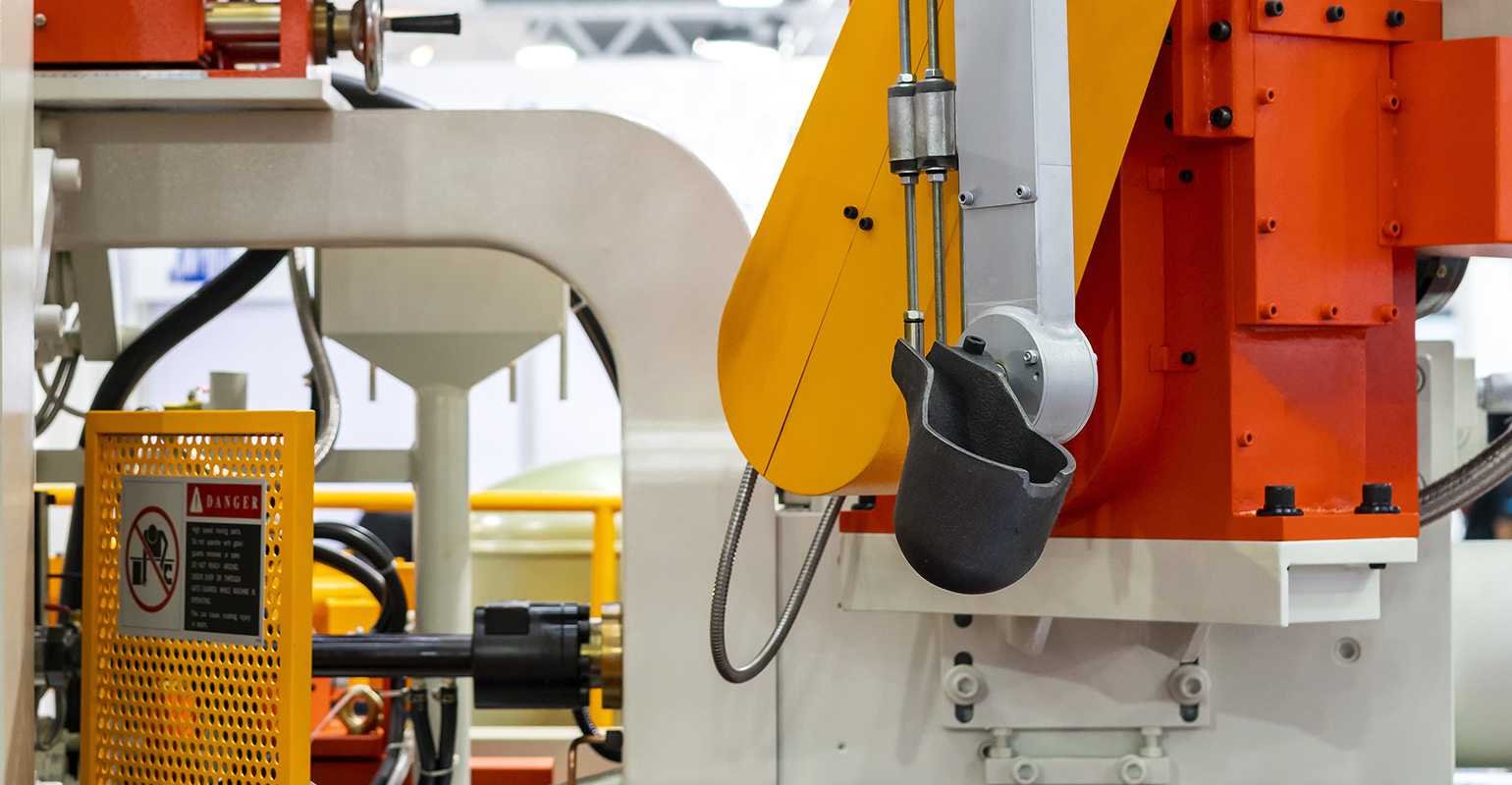 Close up, ladle and mechanical arm of a high-pressure aluminum diecasting machine.