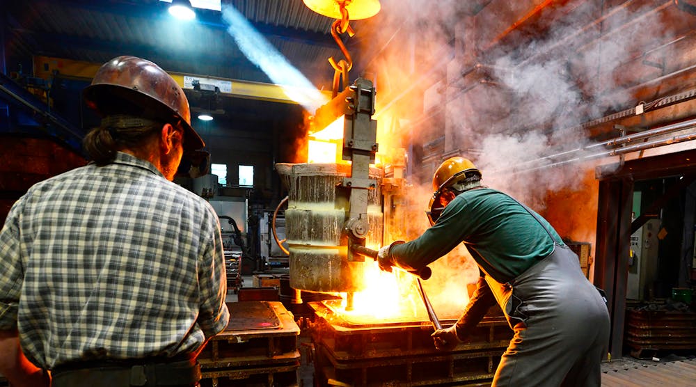 Workers in a foundry casting a metal workpiece - safety at work and teamwork.