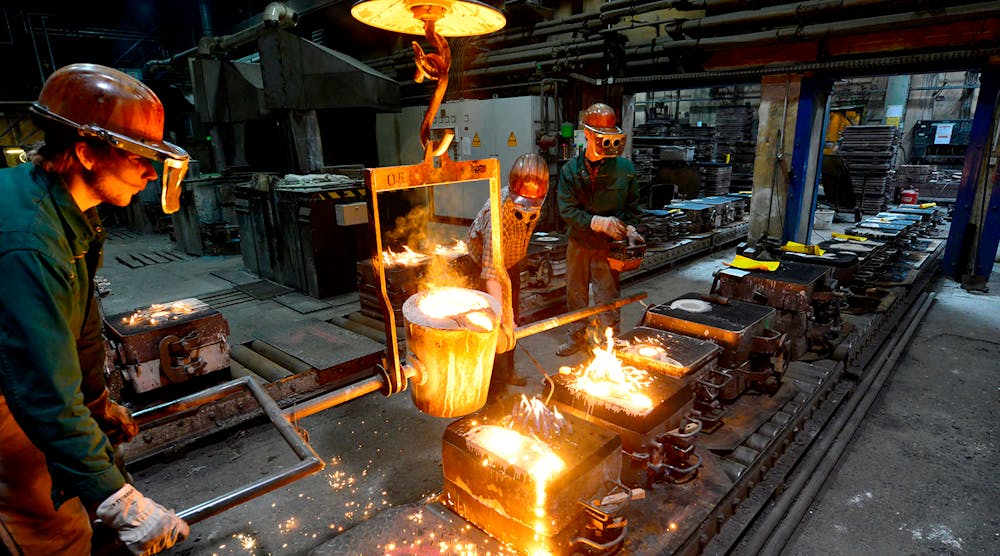 Workers in a foundry casting a metal workpiece; safety at work; teamwork.