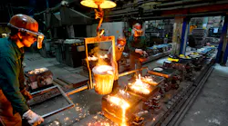 Workers in a foundry casting a metal workpiece; safety at work; teamwork.