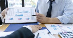 Businessmen evaluating costs and performance charts. Businessmen evaluating costs and performance charts.