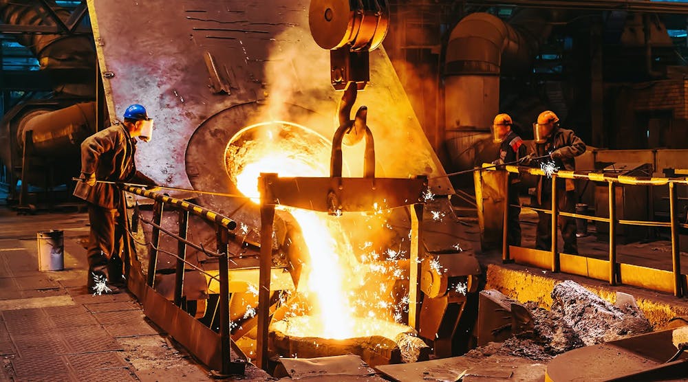 Foundry workers pouring molten iron pouring into a ladle.