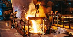 Foundry workers pouring molten iron pouring into a ladle. Foundry workers pouring molten iron pouring into a ladle.