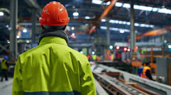 Industrial worker in a factory wearing safety gear.