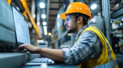 Industrial engineer working at a computer, overseeing production processes and monitoring advanced machinery.