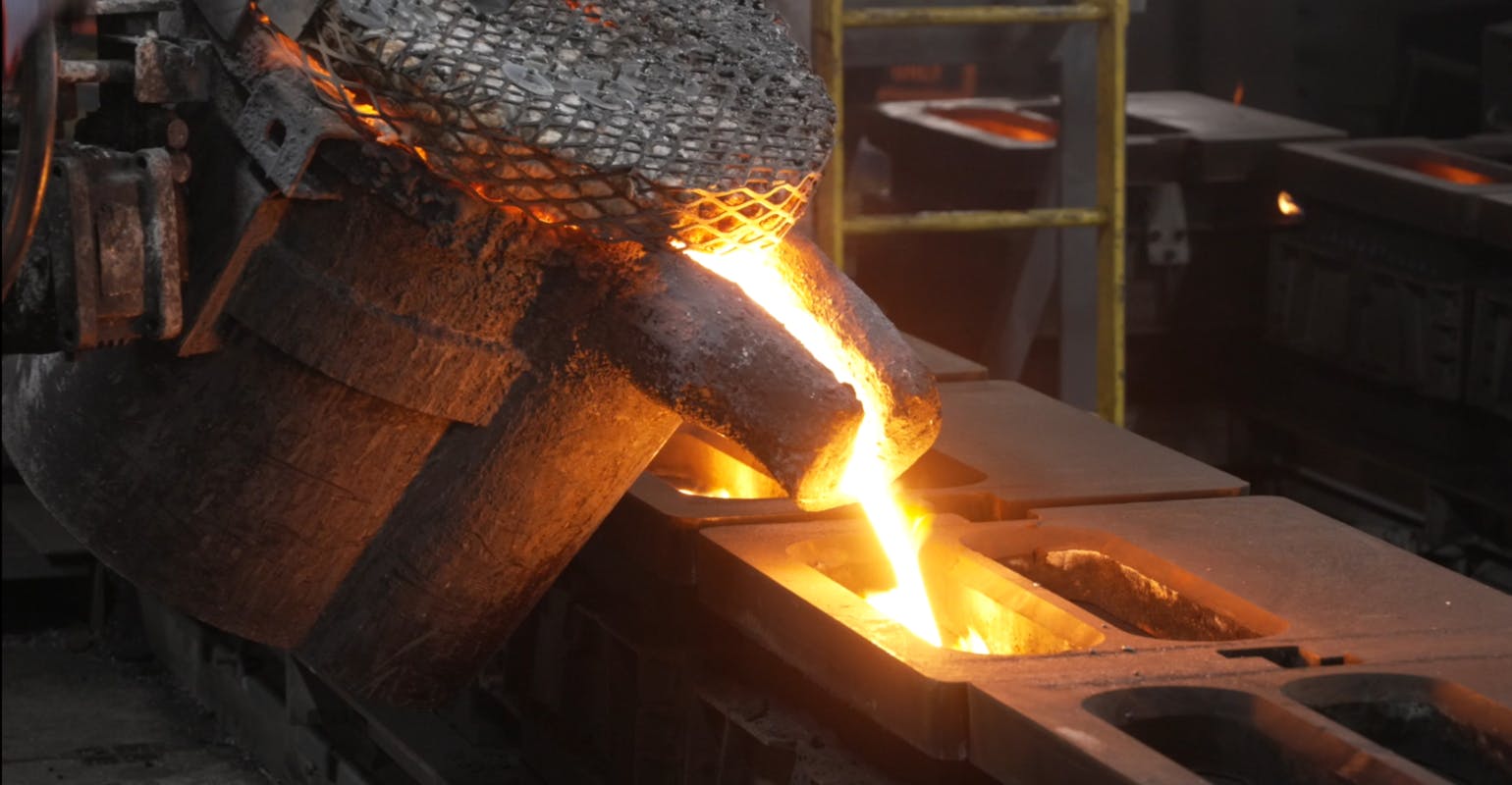 Ladle filling molds with molten iron.