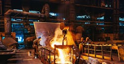 Foundry workshop interior, molten iron pouring from furnace into ladle as workers control the process. Foundry workshop interior, molten iron pouring from furnace into ladle as workers control the process.