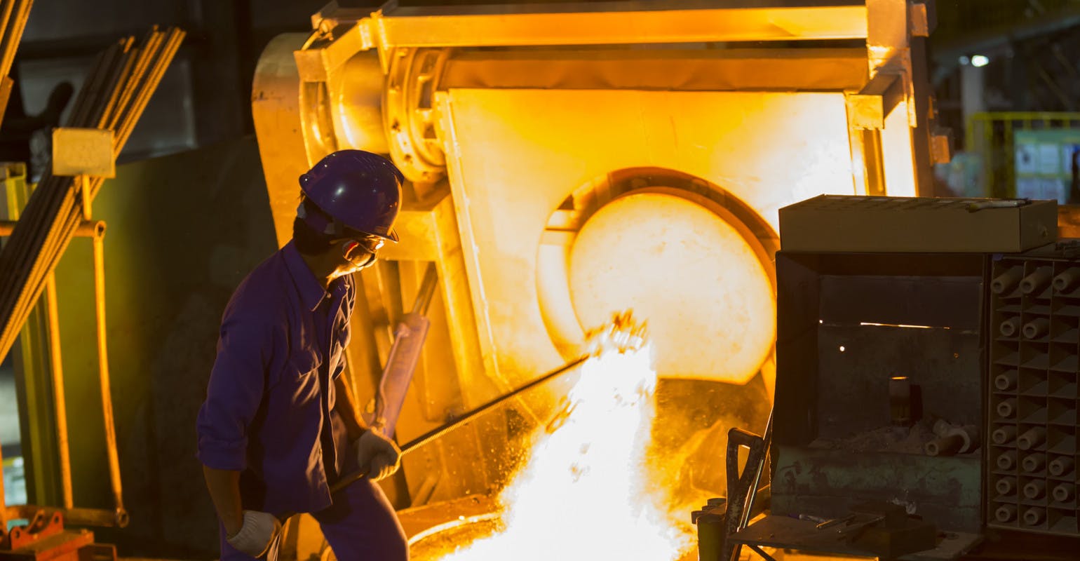 Operator removes iron from electric induction melting furnace.