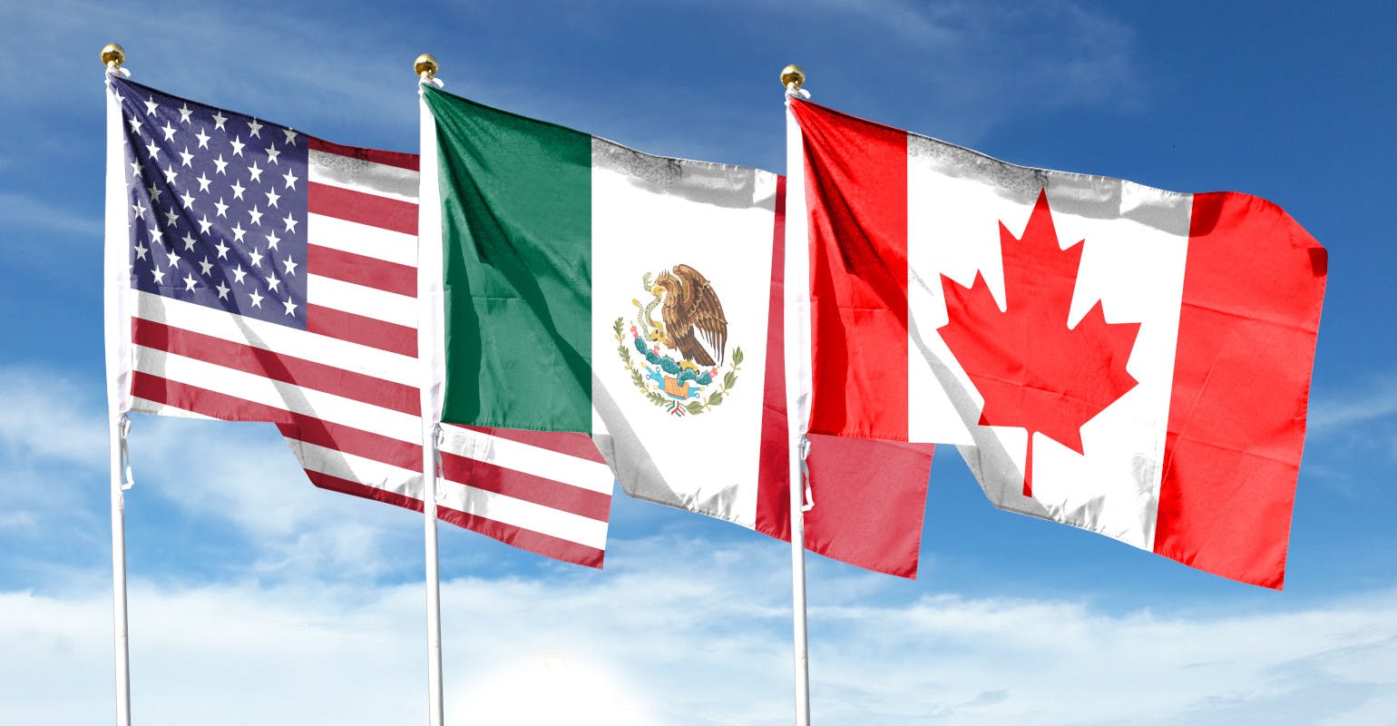 Flags of USA and Canada and Mexico against a cloudy sky