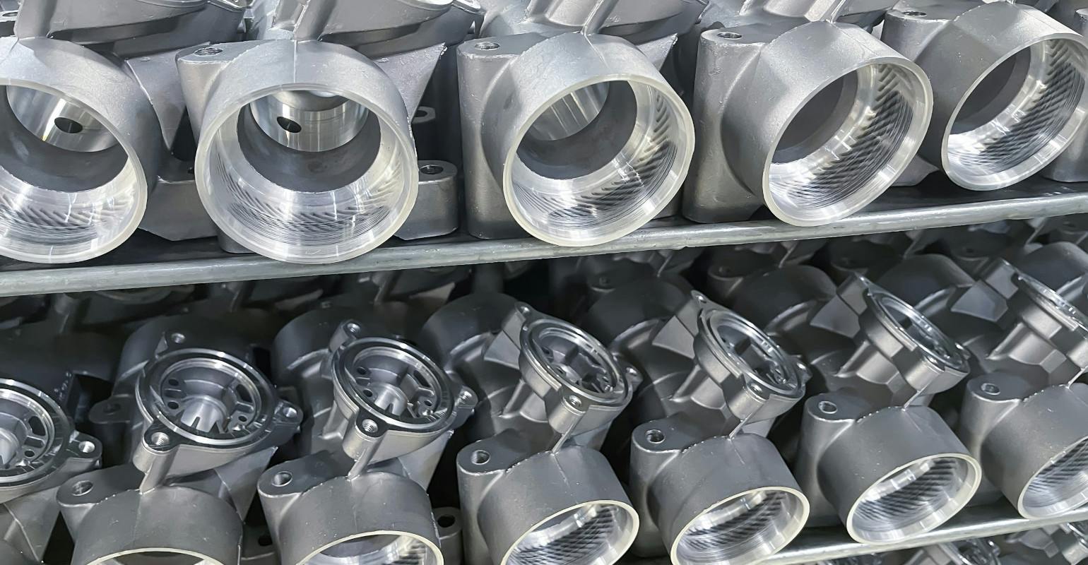 Machined, diecast automotive aluminum parts on a rack.